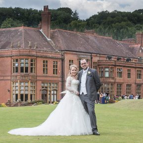 Wedding couple stand in front of Woldingham School, Surrey.