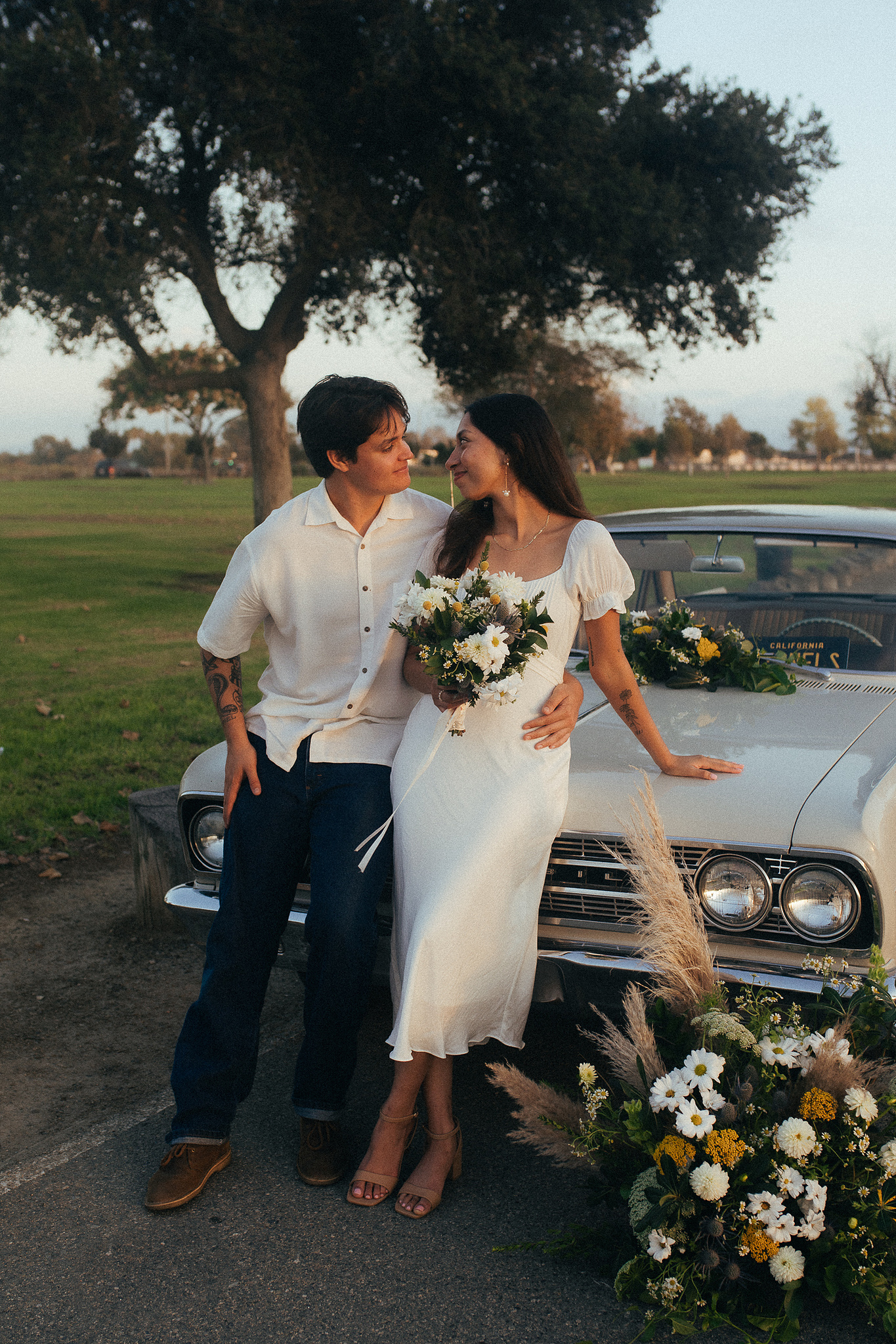 Two young lovebirds pose in front of their vintage car for their engagement photo session in Fairview Park, Costa Mesa, CA. Vibes are film and romantic. Engagement photography by Aly Rose Photo. California wedding photographer