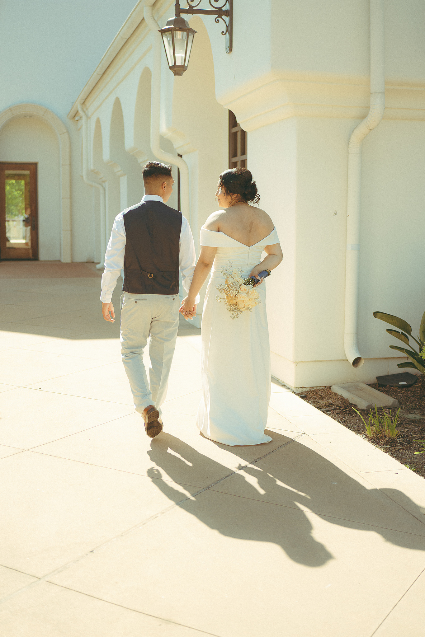 Bride and groom walk away from the camera with their shadows following. A warm, sunny, summer courthouse elopement at Laguna Hills Civic Center, Orange County, CA. Elopement, wedding, portrait, engagement photography by Aly Rose Photo. Romantic, dreamy