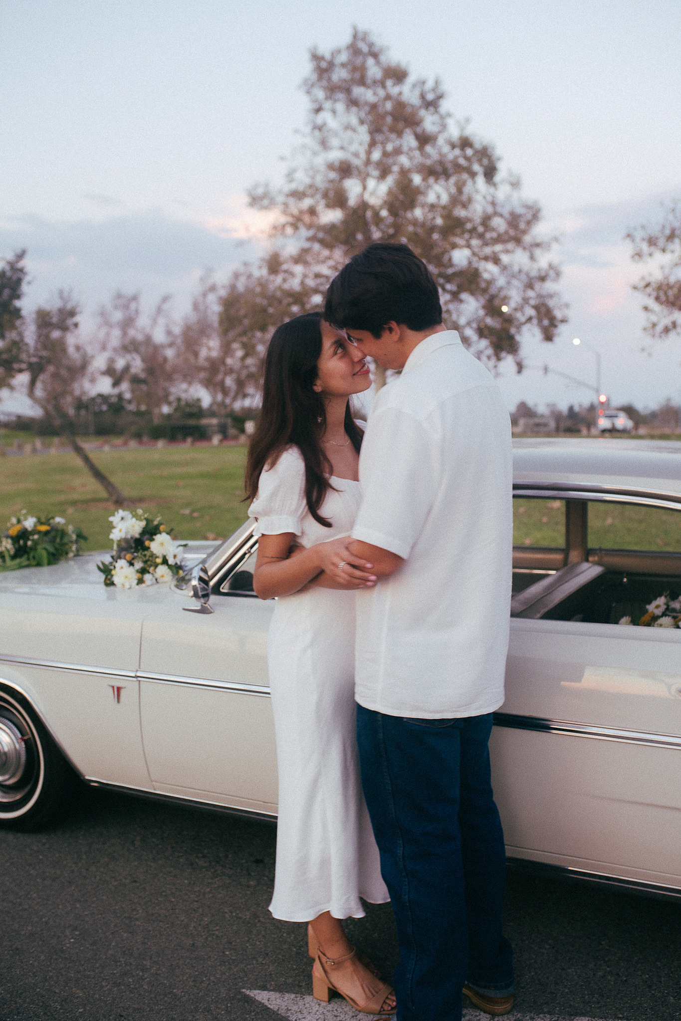 Two young lovebirds dance in front of their vintage car for their engagement photo session in Fairview Park, Costa Mesa, CA. Vibes are film and romantic. Engagement photography by Aly Rose Photo. California wedding photographer