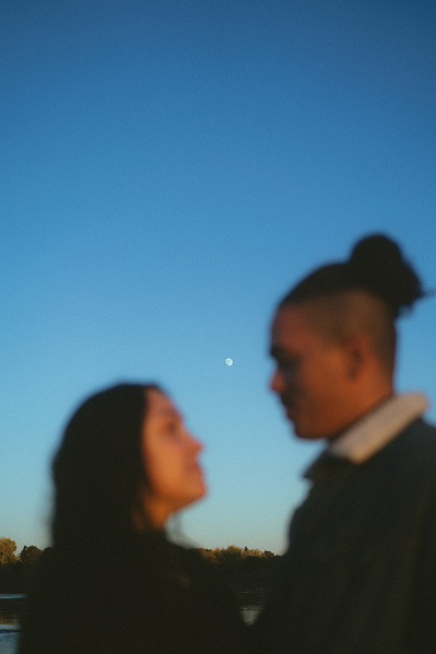 A couple stars into each others eyes. They're out of focus, but the moon in the clear blue sky right in between them is. The sunset hits their faces. Vibes are romantic, dreamy, organic. SoCal film and digital Wedding elopement photographer Aly Rose Photo