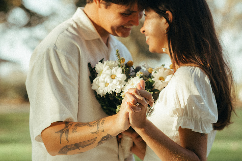 Two young lovebirds pose in a cottage-core white dress and dress shirt in the afternoon sun for their engagement photo session in Fairview Park, Costa Mesa, CA. Engagement photography by Aly Rose Photo. California wedding photographer