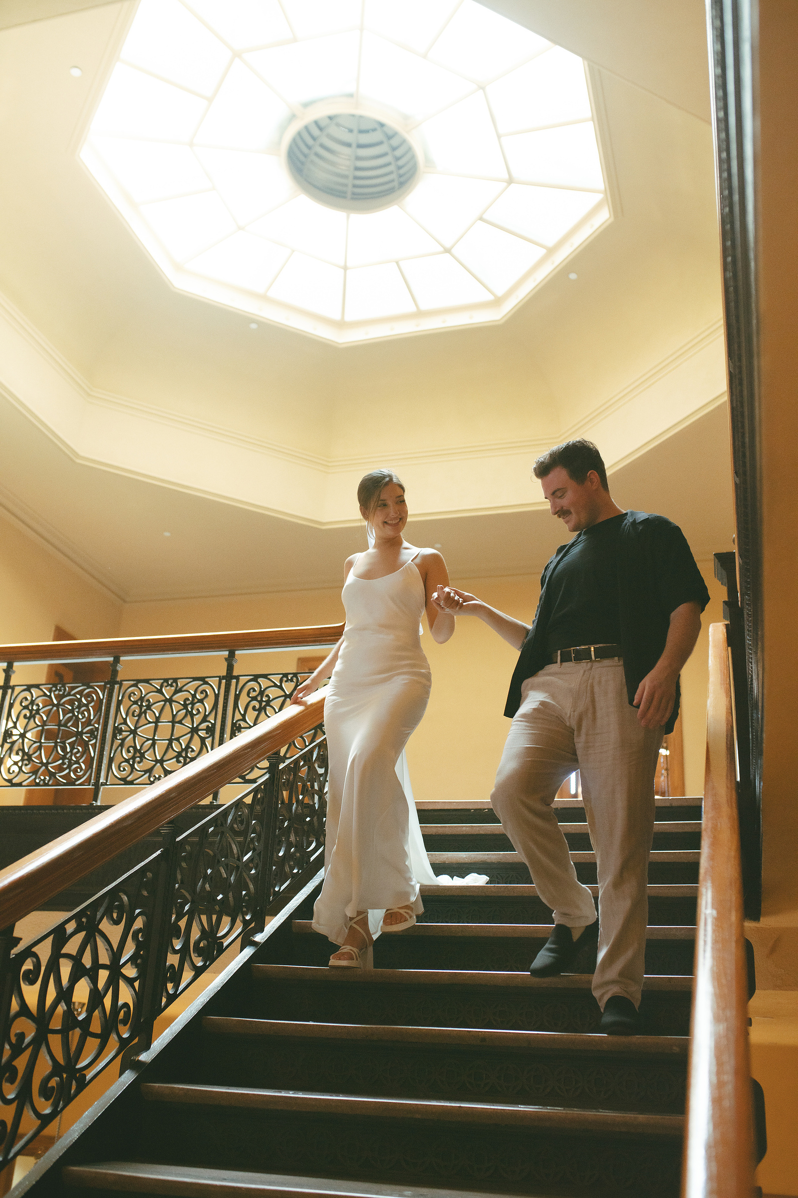 Bride and groom walk down the central staircase at their courthouse wedding ceremony, Old Orange County Courthouse, Santa Ana, CA, Aly Rose Photo, natural light engagement, elopement, wedding, portrait, lifestyle photographer in Southern California