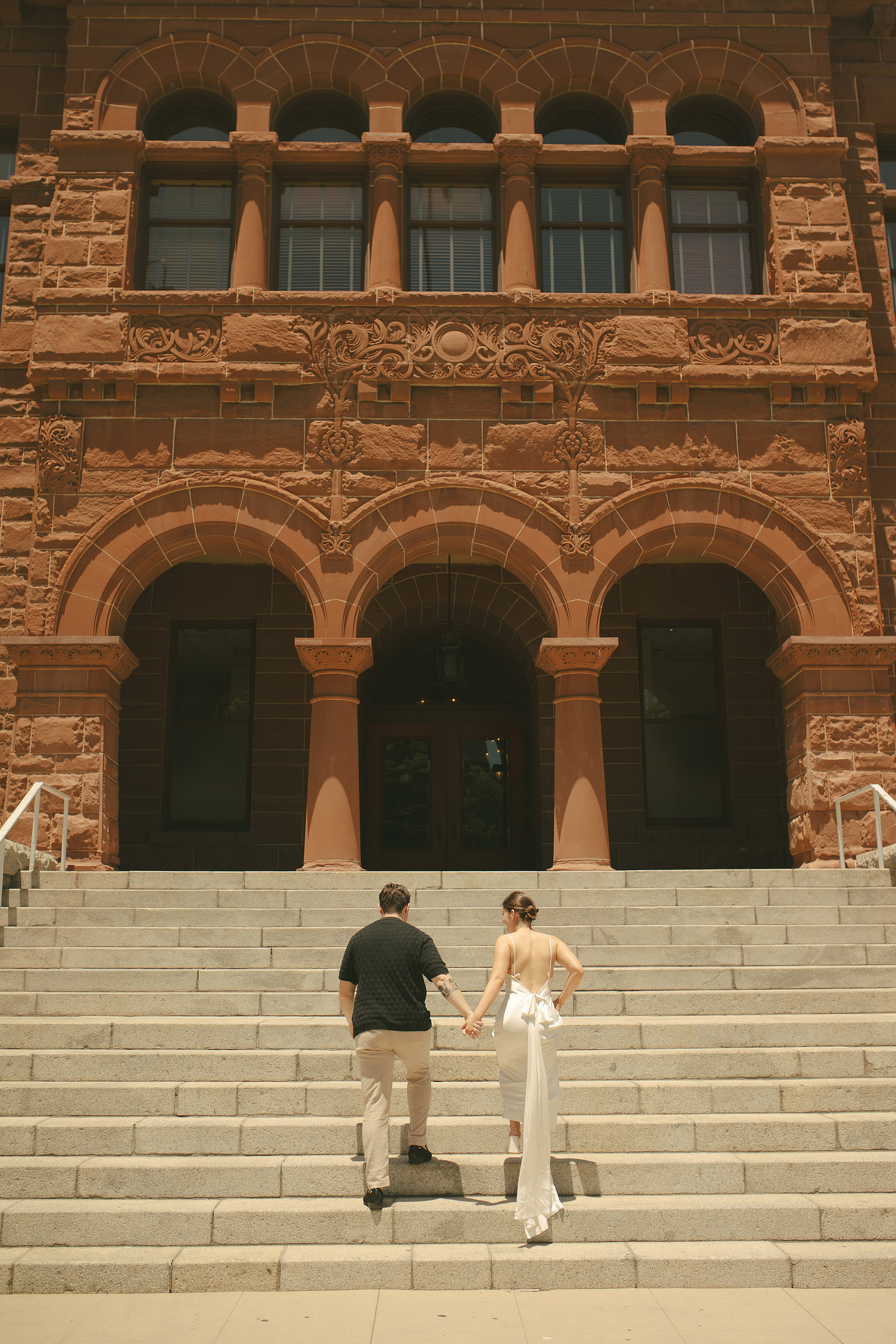 Bride and groom hold hands and walk up the steps to their courthouse wedding ceremony, Old Orange County Courthouse, Santa Ana, CA, Aly Rose Photo, natural light engagement, elopement, wedding, portrait, lifestyle photographer, Southern California