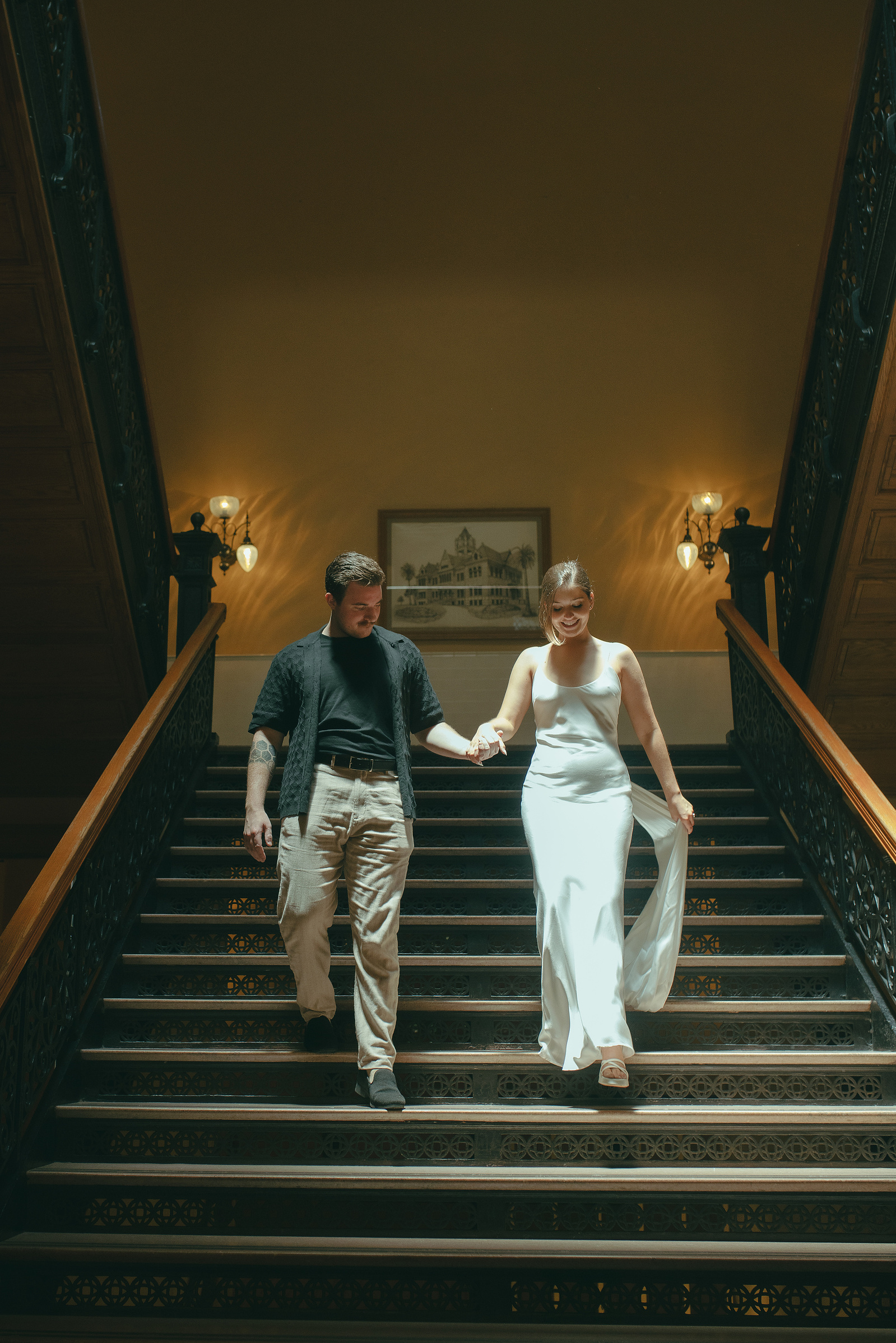 Bride and groom hold hands and walk down the grand central staircase to their courthouse wedding ceremony, Old Orange County Courthouse, Santa Ana, CA, Aly Rose Photo, natural light engagement, elopement, wedding, portrait, lifestyle photographer in SoCal