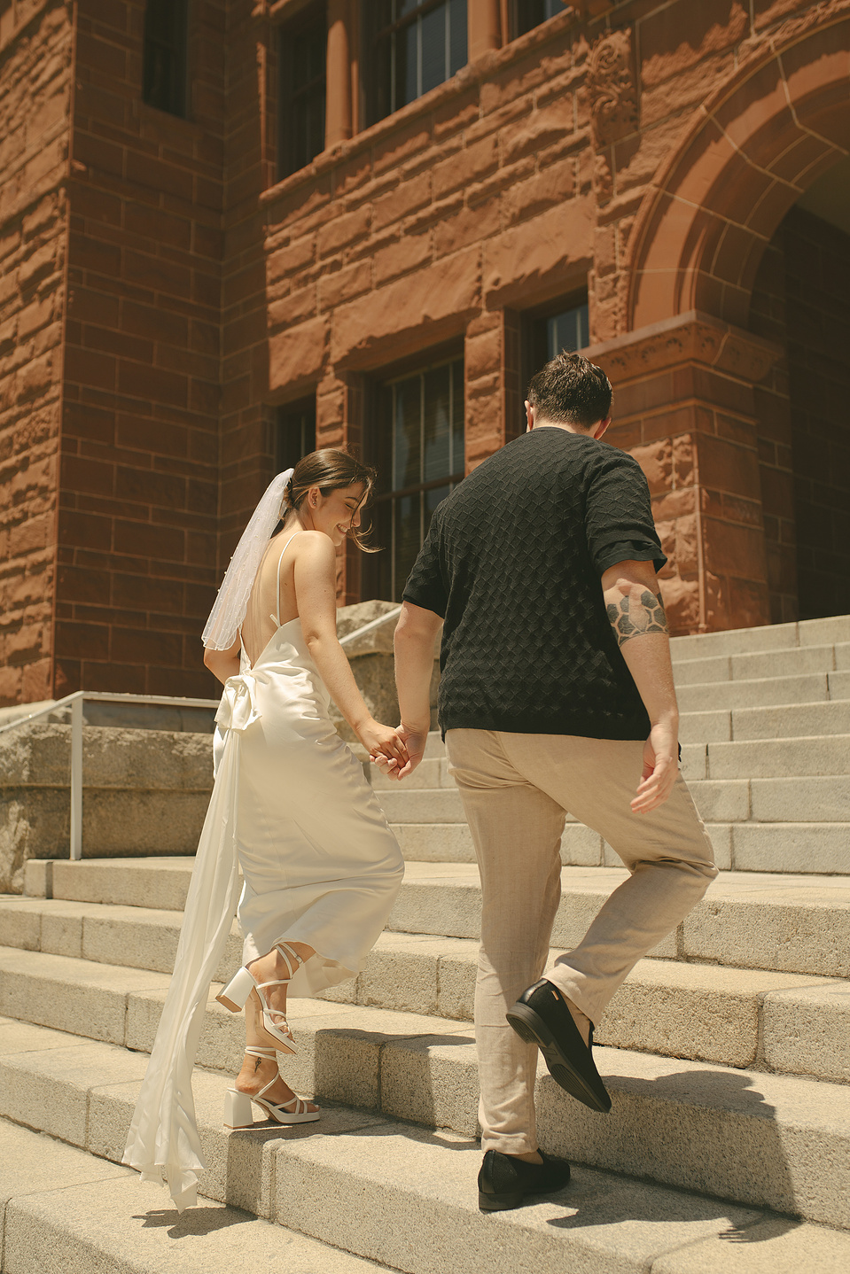 Bride and groom take portraits walking up the front stairs at their courthouse wedding ceremony, Old Orange County Courthouse, Santa Ana, CA, Aly Rose Photo, natural light engagement, elopement, wedding, portrait, lifestyle photographer SoCal