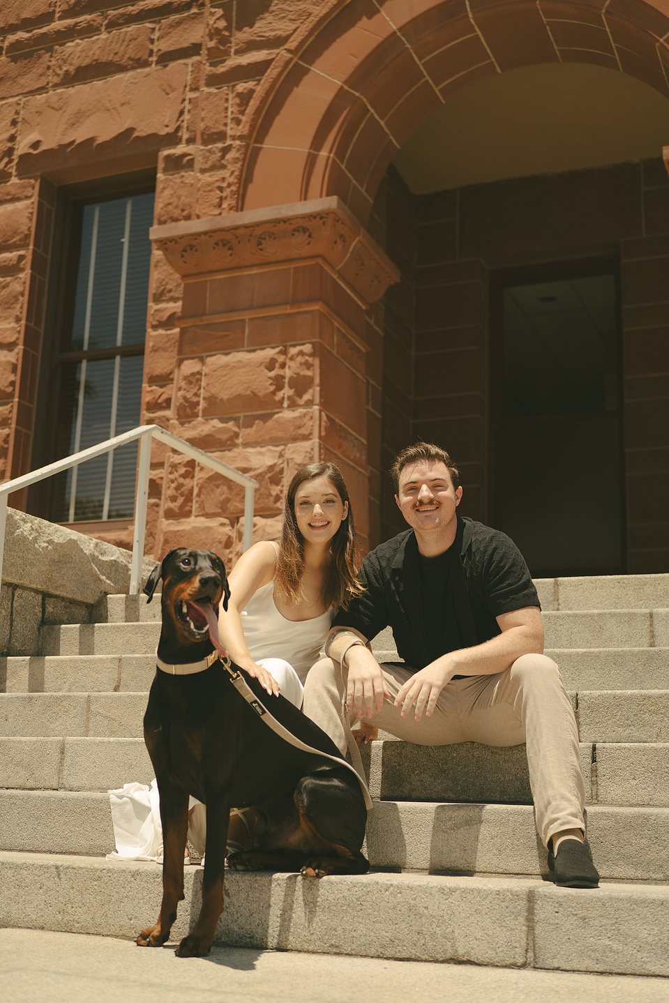 Bride and groom take family portraits with their dog on the front stairs at their courthouse wedding ceremony, Old Orange County Courthouse, Santa Ana, CA, Aly Rose Photo, natural light engagement, elopement, wedding, portrait, lifestyle photographer