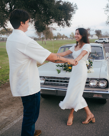 Two young lovebirds dance in front of their cute, vintage car adorned with floral arrangements for their romantic, vintage vibes engagement session. Costa Mesa, CA. Natural light wedding, engagement, elopement photography by Aly Rose Photo. California