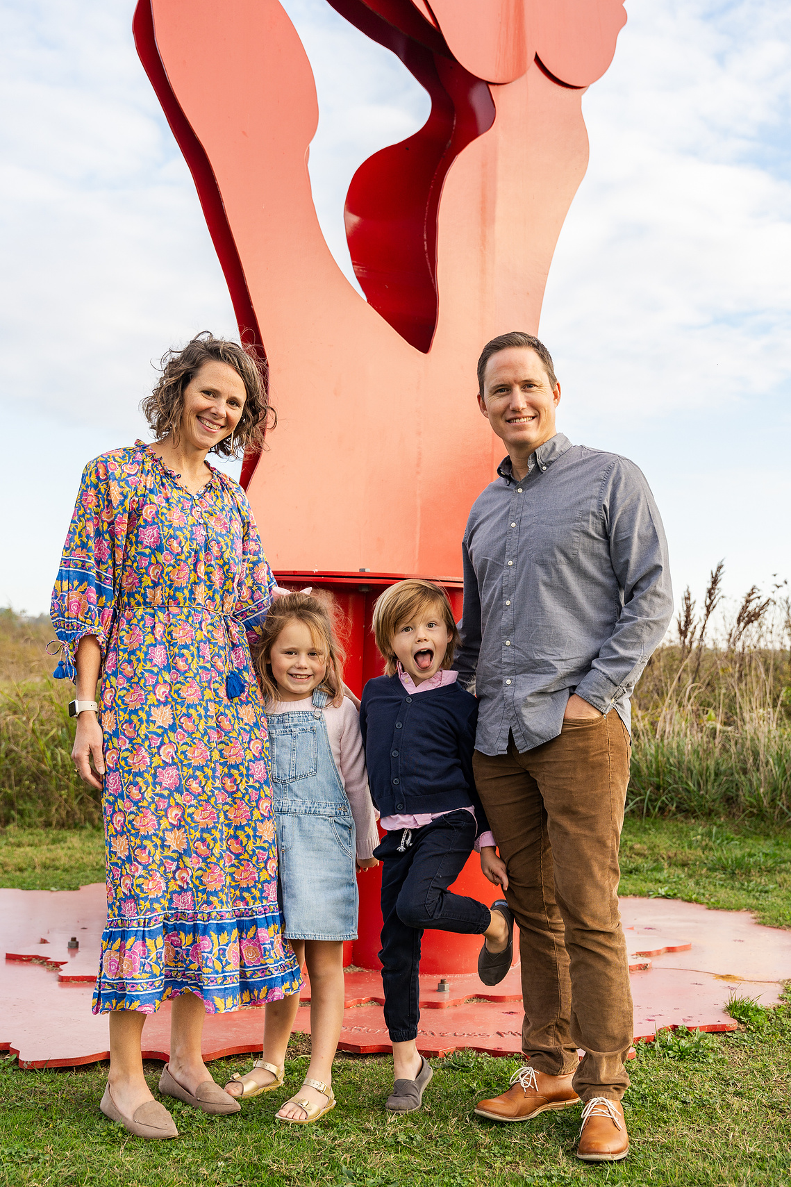 Family portrait at Montague Sculpture Field with golden hour lighting and artistic sculptures in the background.