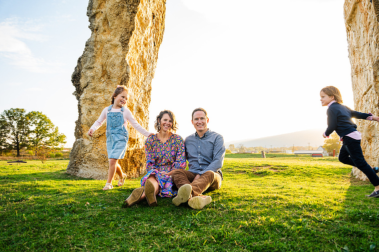 Family portrait at Montague Sculpture Field with golden hour lighting and artistic sculptures in the background.