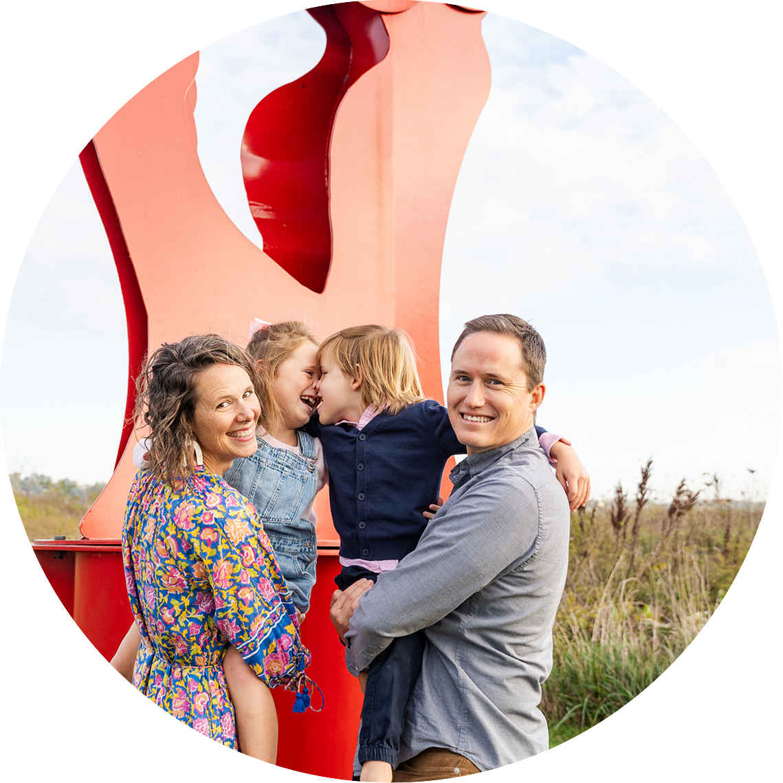 Family portrait at Montague Sculpture Field with golden hour lighting and artistic sculptures in the background.