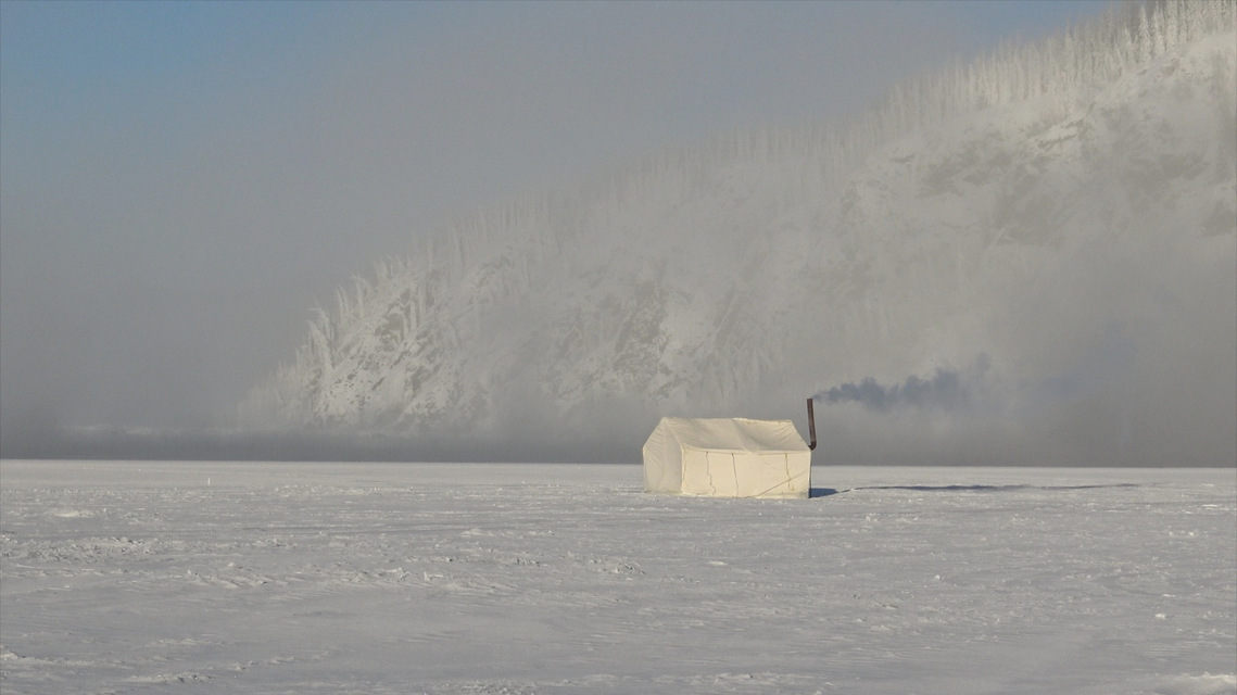 ice fishing tent on the Yukon River near Dawson City, Yukon, with ice fog in the background