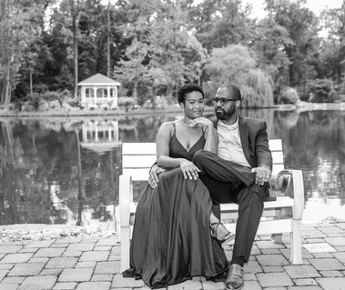 bride and groom sitting on bench in front of lake.