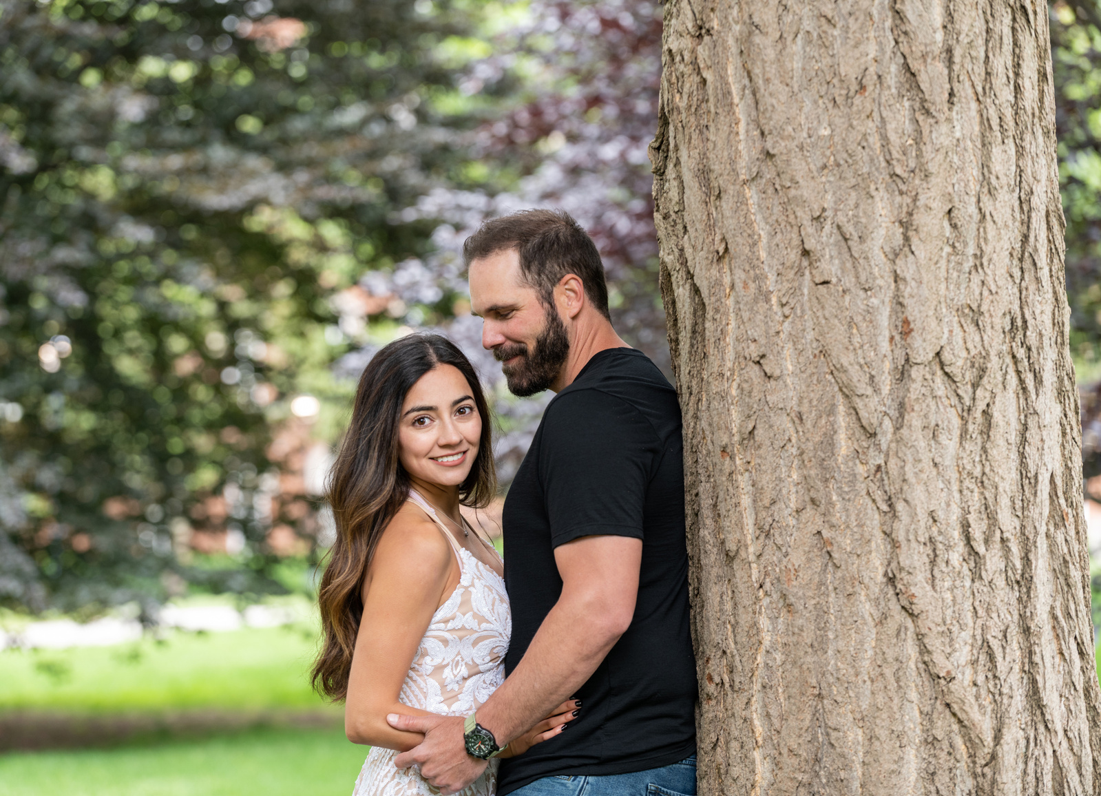 woman and man leaning against tree.