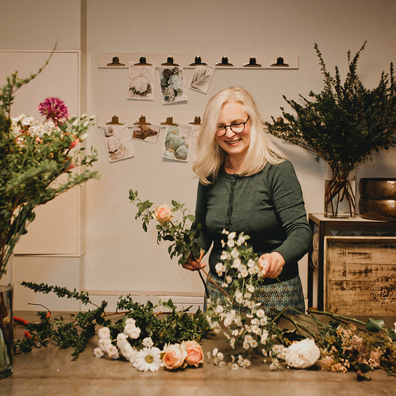Bei einem ungestellten Business Fotoshooting in Berlin bindet eine Floristin in ihrem Atelier einen Blumenstrauß. 
