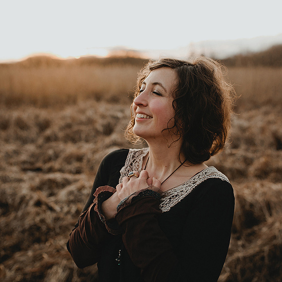 Eine Künstlerin genießt bei einem entspannten Portraitshooting in Berlin die Abendsonne und nimmt mit geschlossenen Augen einen tiefen Atemzug. 