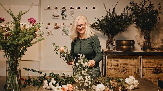Während einer authentischen Businessreportage in Berlin bindet eine Floristin in ihrer Werkstatt einen Strauß.