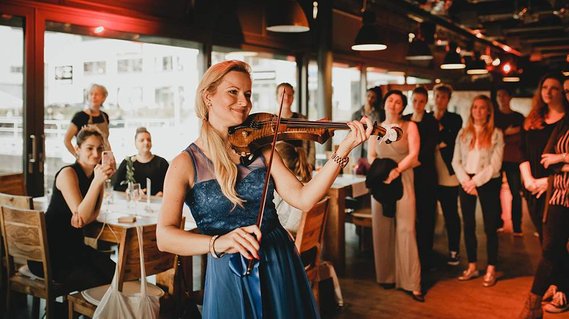 Eventfotografie einer Firmenveranstaltung in Berlin. Eine Musikerin spielt für die Gäste auf der Geige. 