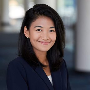 Professional headshot of Asian woman, smiling on a blurred environmental background for her Duke E.R.A.S. application.