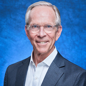 Professional headshot for company website of an older gentleman on a textured blue background.