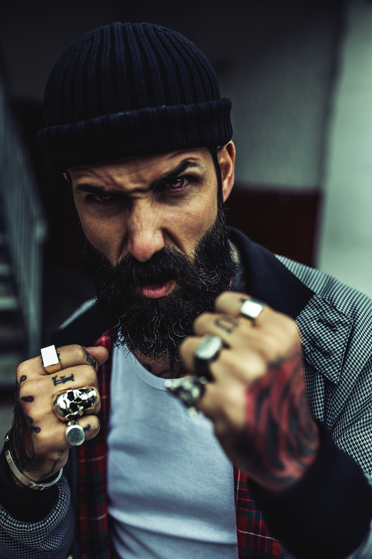 A bearded tattooed man raises his fists up in preparation for a fight.