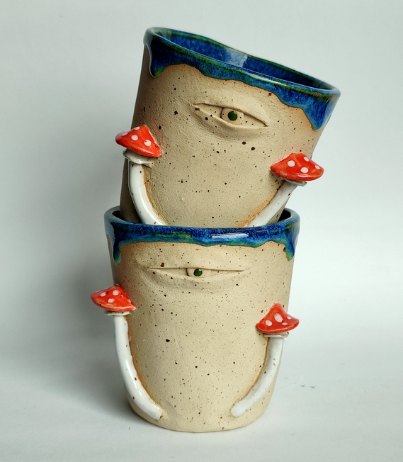 two handmade ceramic mugs with an eye and mushrooms