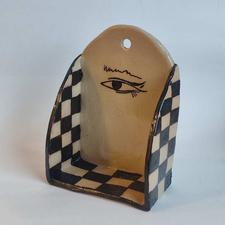 One handmade ceramic shef or altar painted in black and white squares and one eye in the middle.