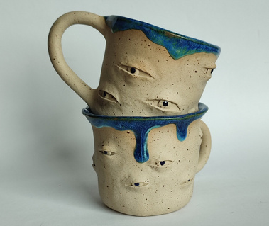 Two handmade ceramic mug with many eyes around.