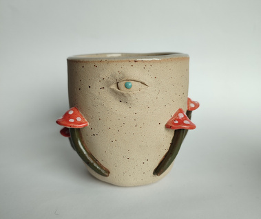 One handmade ceramic mug with mushrooms and one eye.