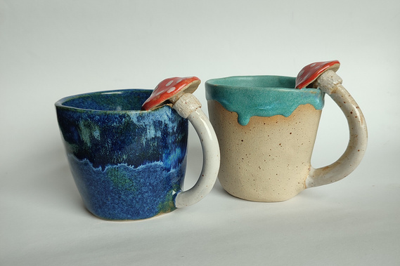 two blue handmade ceramic mugs with a mushroom handle