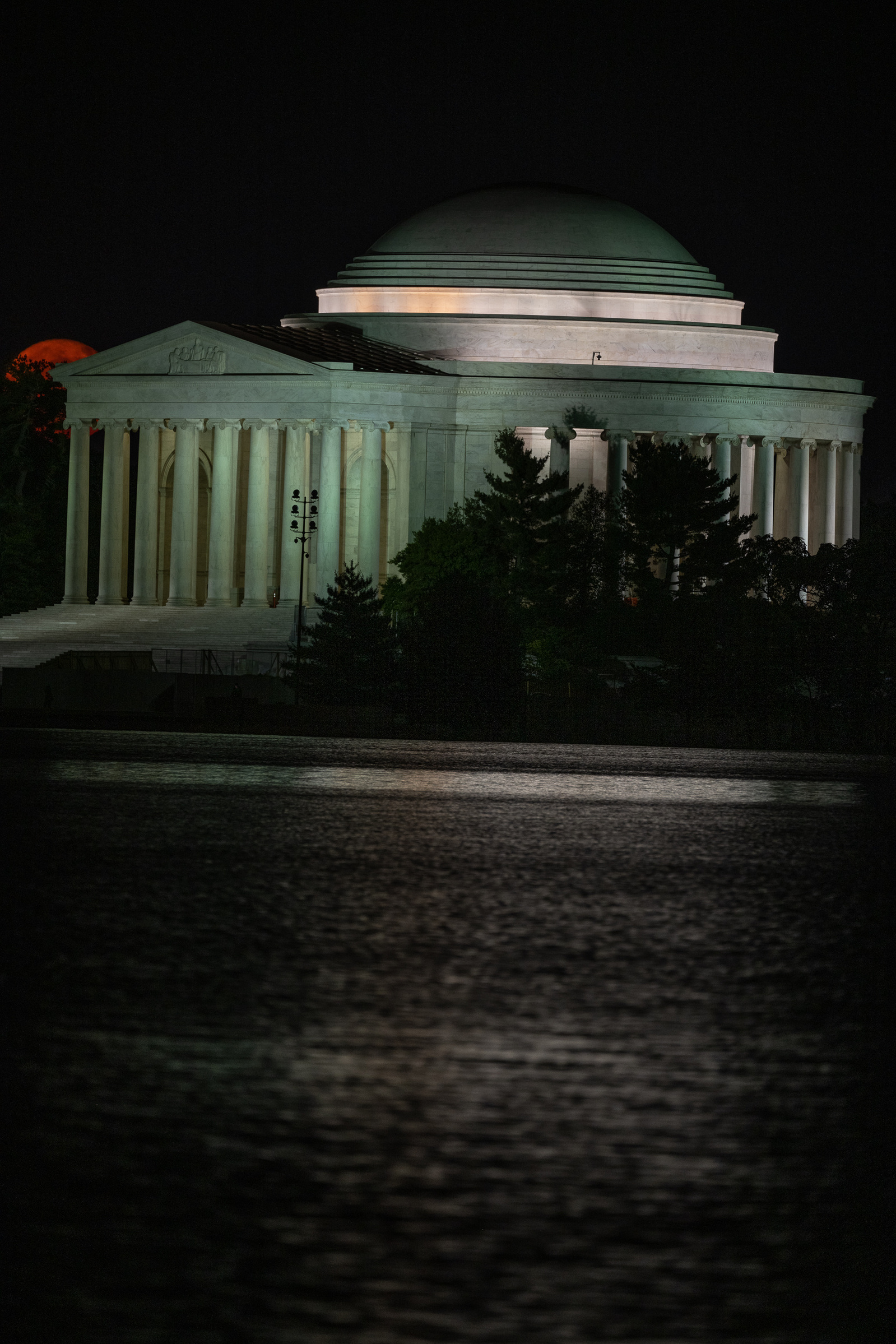 Orange-colored  full moon beginning to rise behind the portico of Jefferson Memorial, Washington DC