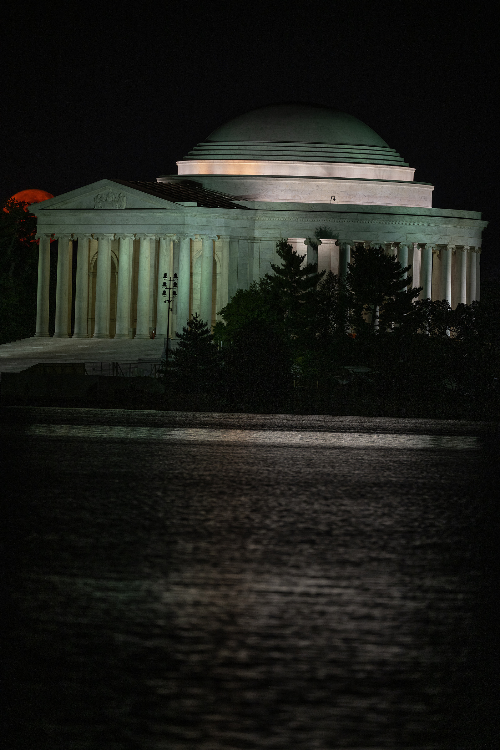 Orange-colored  full moon beginning to rise behind the portico of Jefferson Memorial, Washington DC