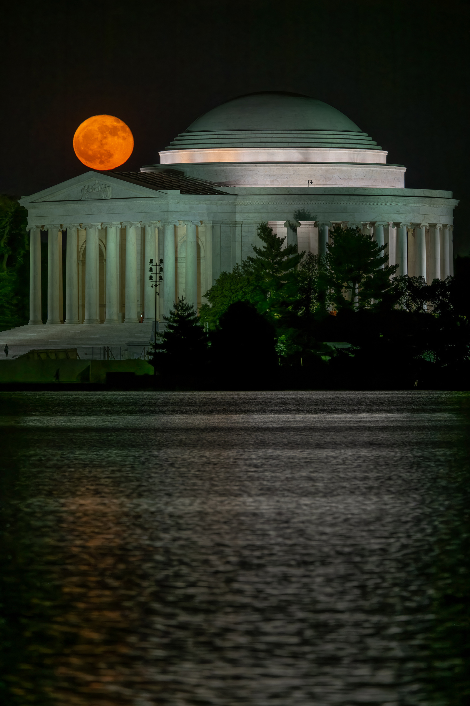 Orange-colored  full moon just over the portico of Jefferson Memorial, Washington DC