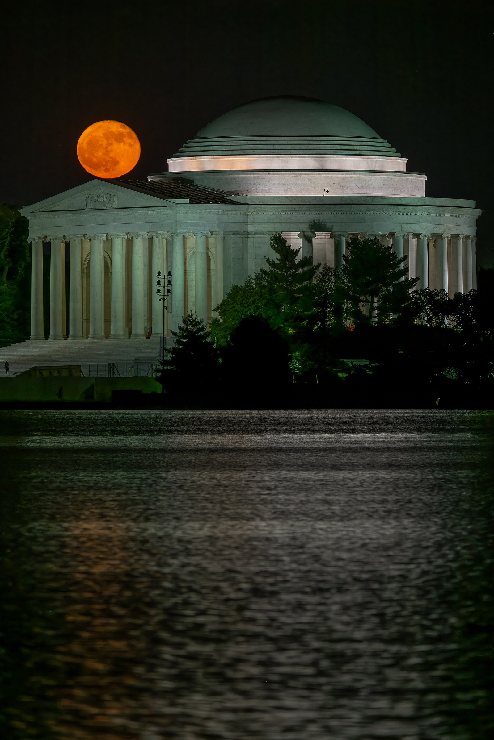 Orange-colored  full moon just over the portico of Jefferson Memorial, Washington DC