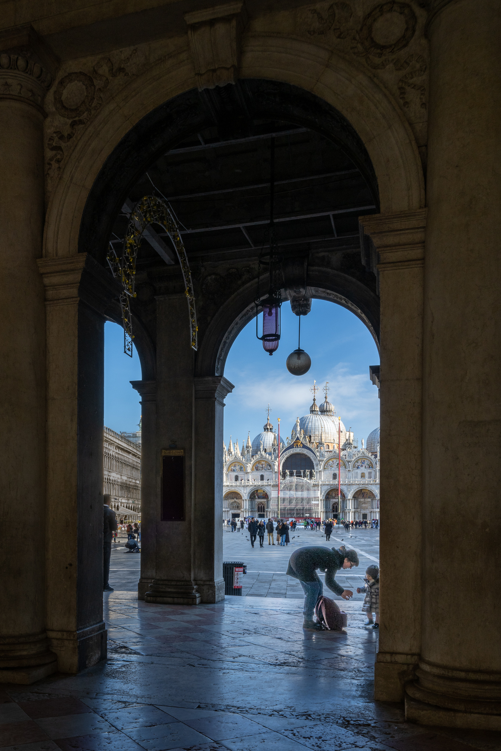 Mother with little girl framed in an archway with San Marco cathedral basilica of Venice Italy in background