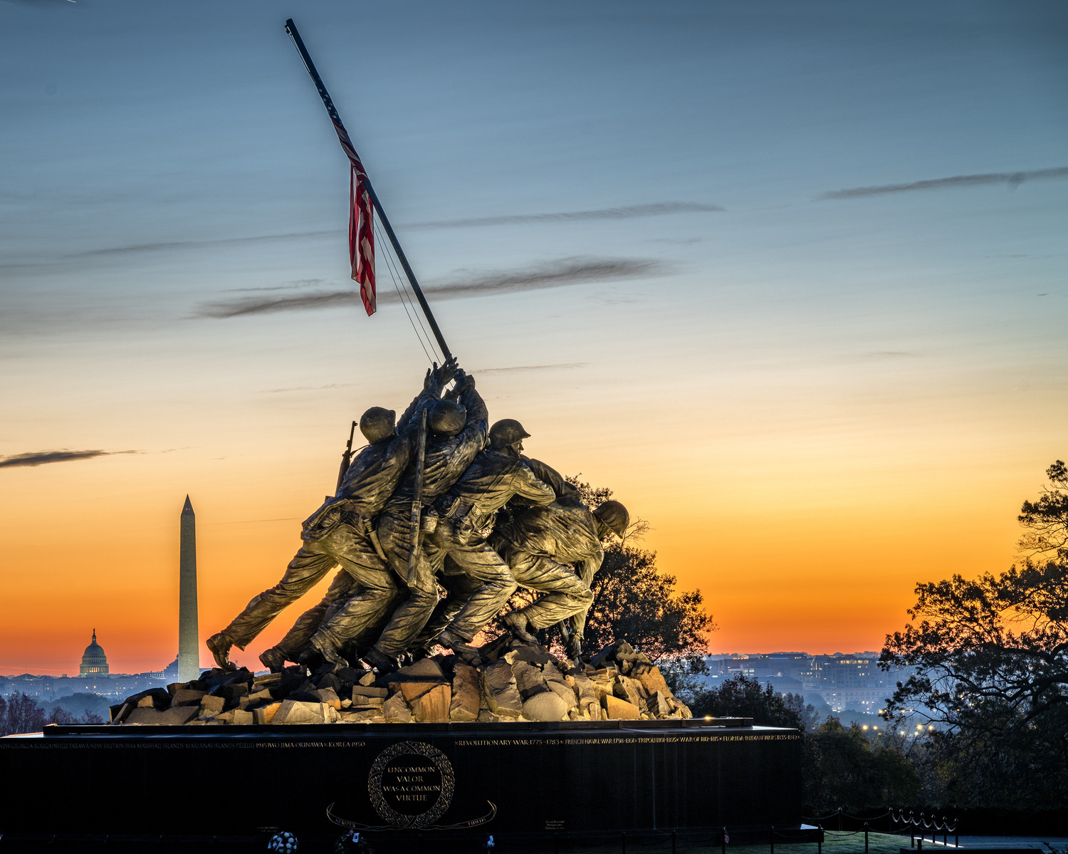 United States Marine Corps Memorial statue in Arlington Virginia  showing Iwo Jima flag raising with sun rising behind soldiers and Washington Monument in distance
