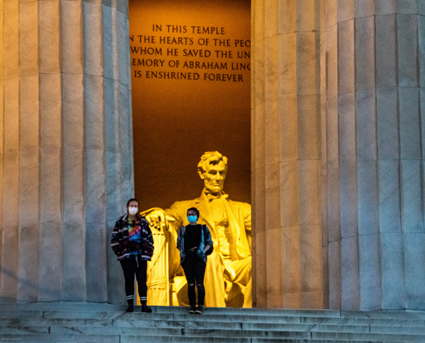 Two people framed by pillars looking out from the Lincoln Memorial, with Lincoln's statue behind them