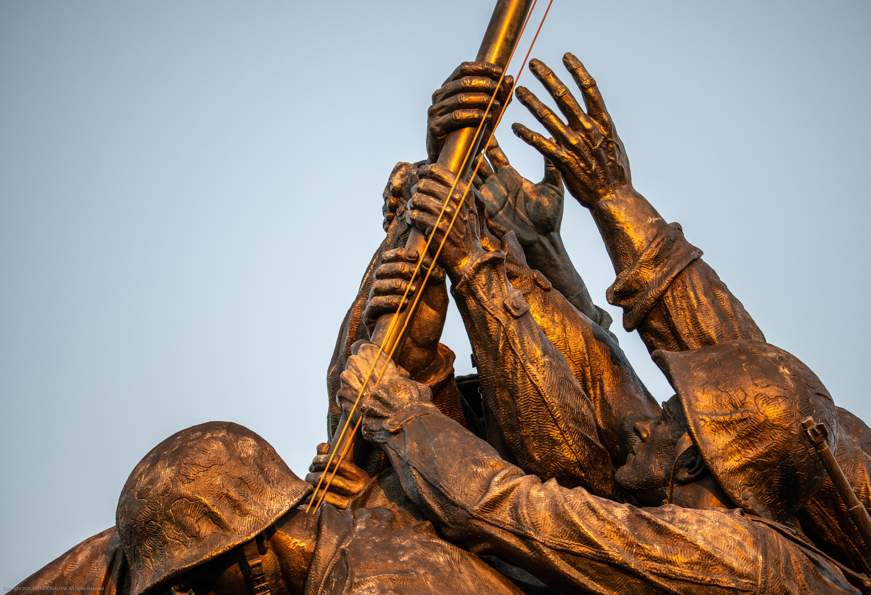 Closeup of hands of the soldiers grasping flagpole, United States Marine Corps Memorial statue in Arlington Virginia  showing Iwo Jima flag raising 