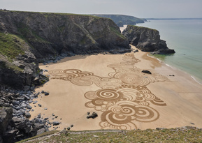 Sculptural walking line made with a rake in wet sand, Cornwall. A single continuous pass marks the surface before tidal erasure.