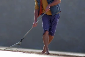 Tony Plant making a tidal drawing on a Cornish beach, using a rake to draw a continuous line in wet sand during a single tidal cycle.