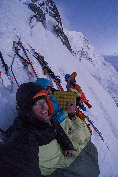 a self portrait of alpine climbers preparing to sleep and camp on the side of a steep snowy and ice cliff face in alaska