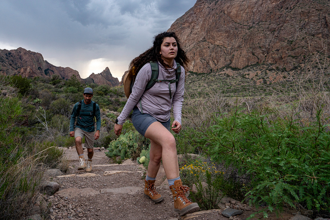 A women and a young man walking in the desert of Western Texas with an afternoon thunder storm quickly approaching.