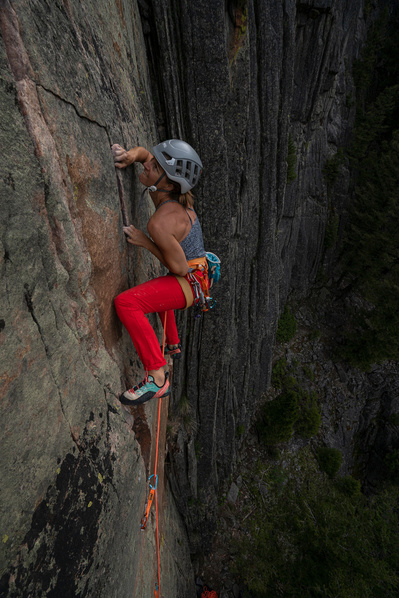 A women showing great determination as she is climbing a steep rock face.