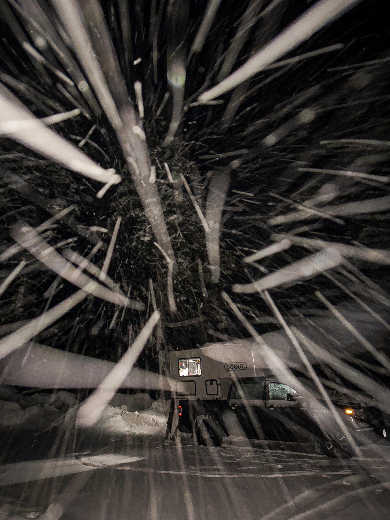 A wild night time photo of illuminated snow flakes darting towards the camera. Slow motion blure gives the image a motion feel.
