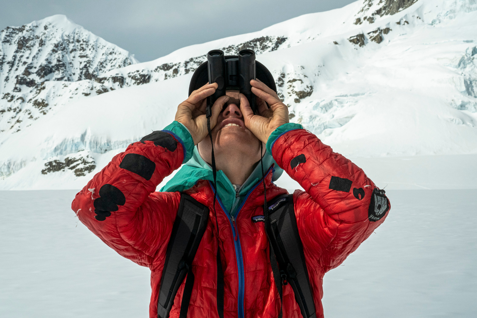 Anne Gilbert Chase eyeing climbing routes through binoculars in the central Alaska Range.