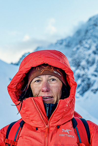 Ines Papert Portrait against a steep jagged snowy mountain with cool light in the background.