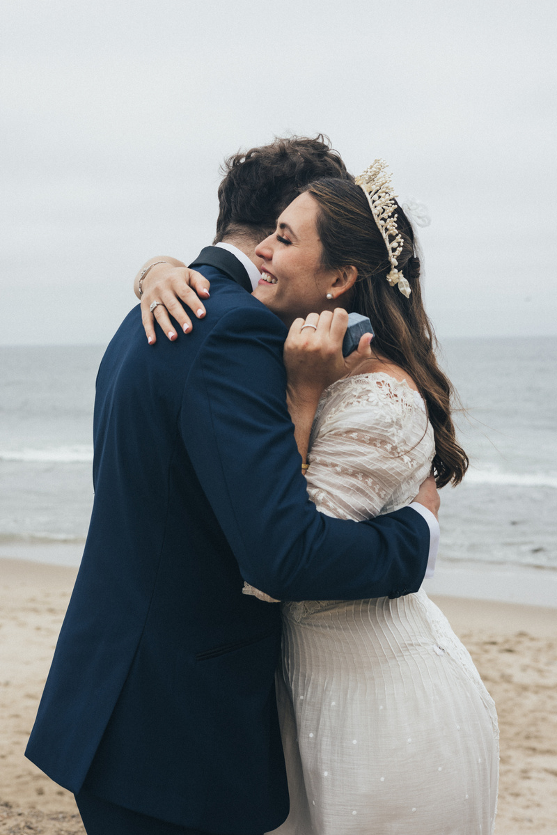 Romantic wedding photography of a moment captured of a bride and groom exchanging rings in Malibu, CA.
