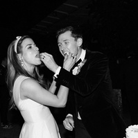Black and white candid flash shot of bride and groom eating cake, captured by Abigail Gorden Photography. A playful and intimate wedding moment.