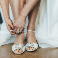 Photography detail shot of bride putting on her wedding shoes.