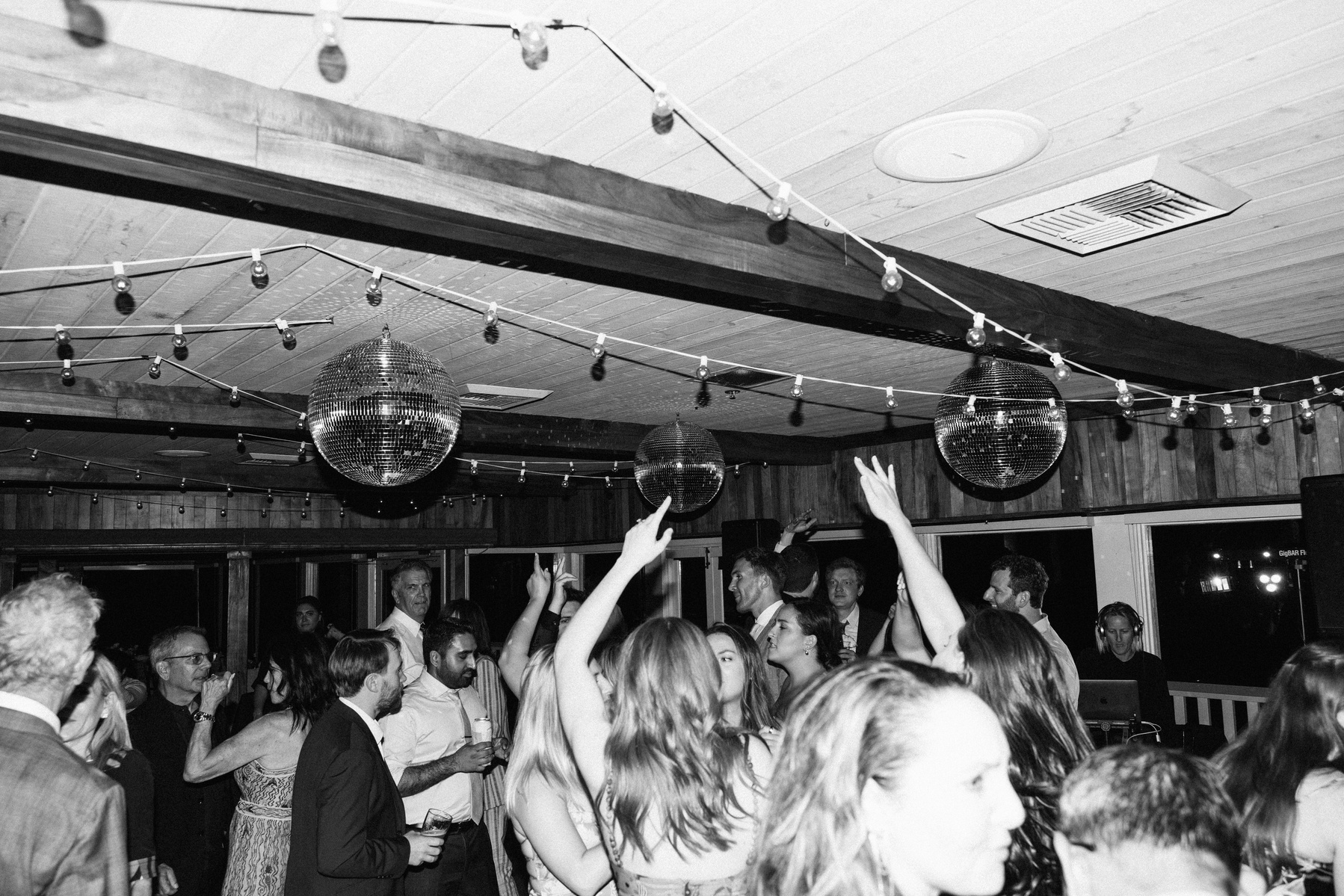 Candid black and white flash wedding photography of family and friends celebrating on the dance floor at Duke's Malibu.